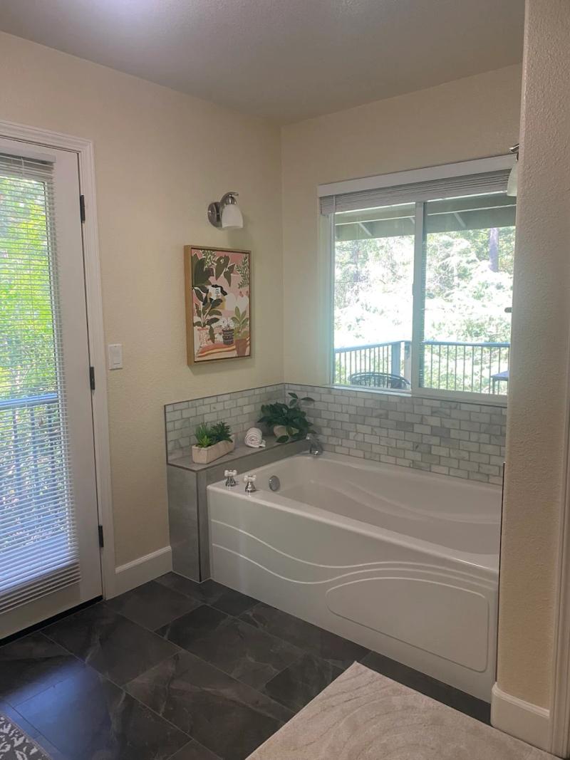 Bathroom remodel featuring a soaking tub, marble tile surround, and modern bathroom finishes.