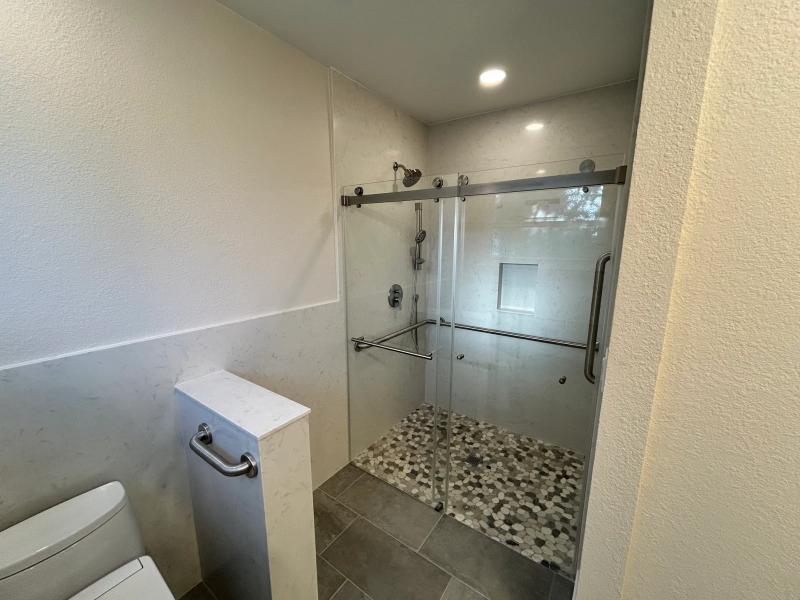 Modern marble bathroom with a frameless glass shower and tiled flooring.