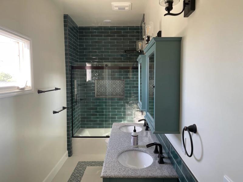 Bathroom tile installation by Roseville tile contractors featuring marble walls, frameless glass shower, and modern flooring.